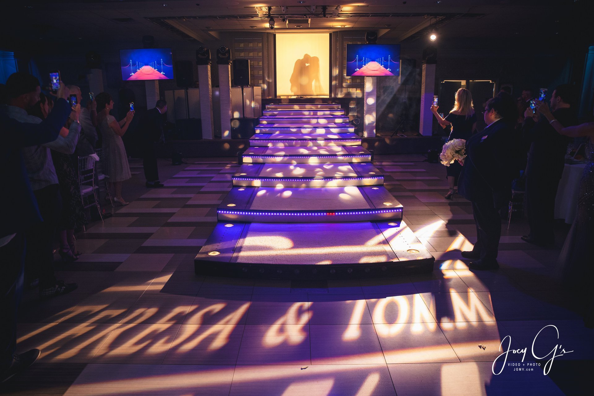 Lit steps in the Encore Ballroom, the couple’s names projected on the floor and guests filming on each side