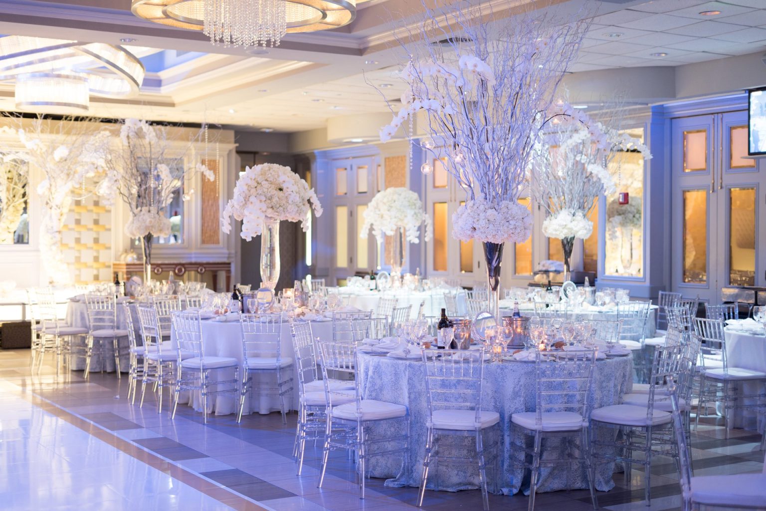 The Encore Ballroom set with tall white branch centerpieces and clear chairs