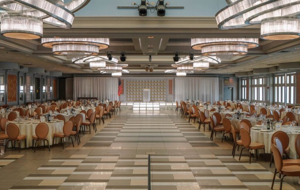 The ballroom set with rounds and a stage for a corporate event