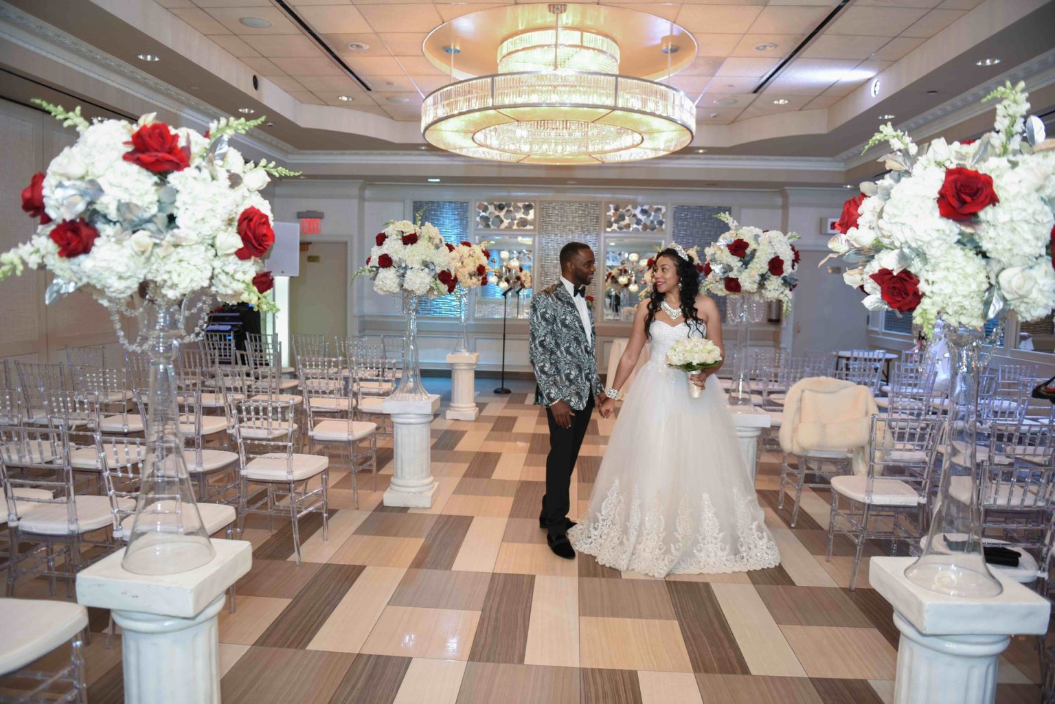 A couple in The Paragon aisle, set for a ceremony with red and white roses