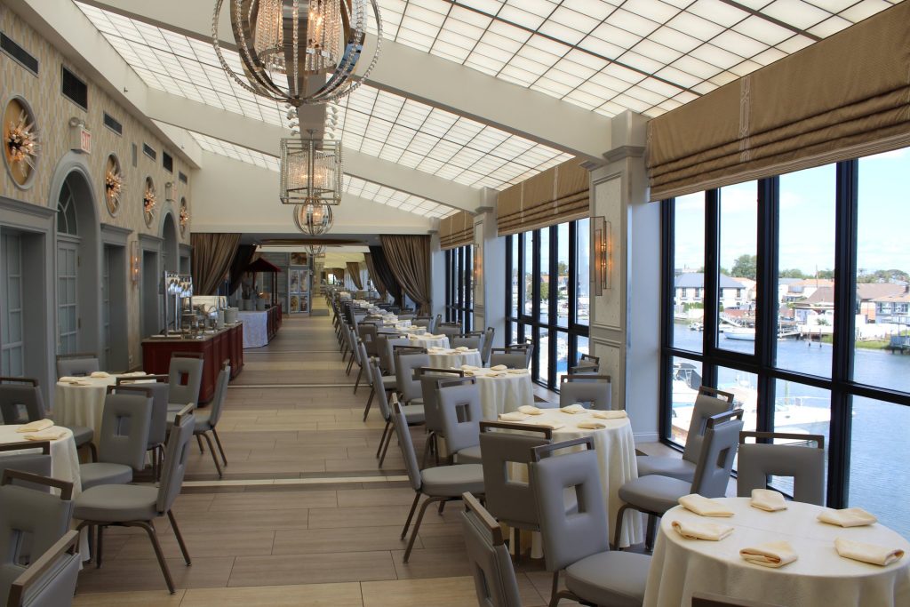 Tables along The Promenade’s windows over the water, with a bar on the left