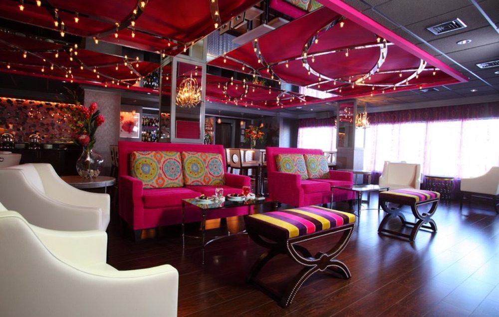 The Rose Lounge, with magenta sofas, white armchairs and a red ceiling strung with lights