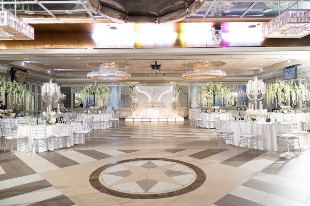 The Encore Ballroom set for a reception, with tall white centerpieces and a star inlaid in the floor
